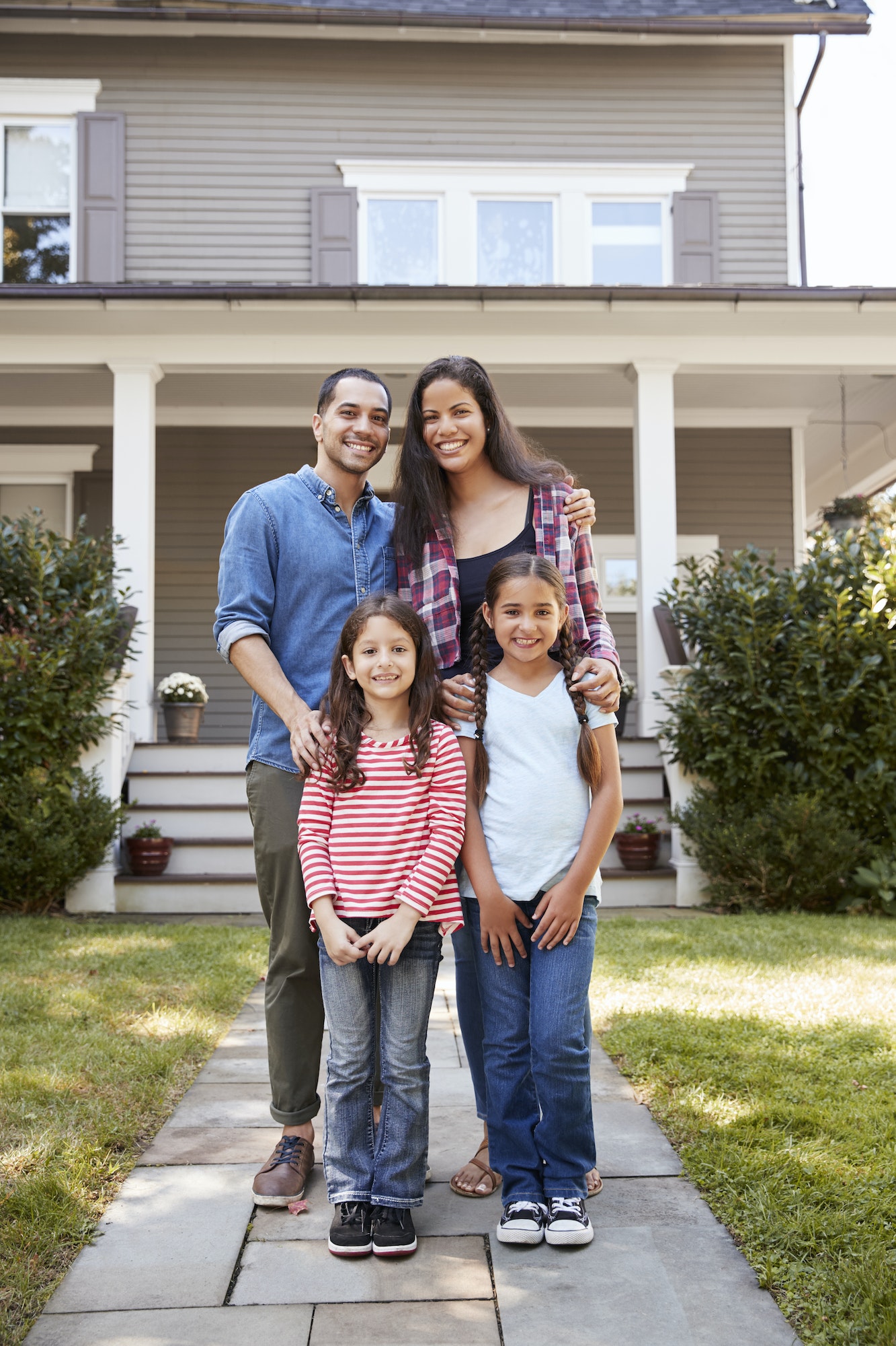 Portrait Of Smiling Family Standing In Front Of Their Home